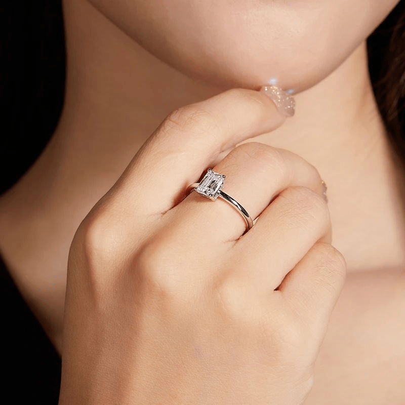 Elegant hand wearing a stunning Lyra 1.0CT moissanite solitaire ring 💍, showcasing its emerald cut sparkle ✨. Perfect for engagement or wedding!