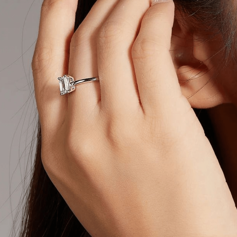Elegant hand wearing a Lyra Moissanite solitaire ring, showing off its stunning 1.0CT emerald-cut sparkle. 💍✨