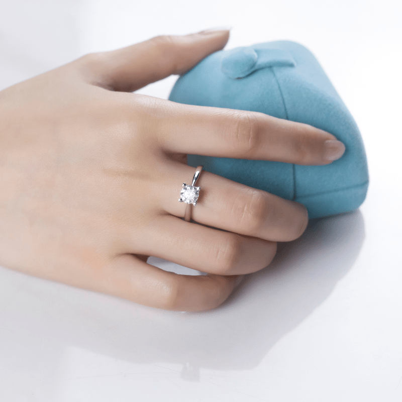 Elegant hand wearing a Marcella Moissanite engagement ring with a 1.0ct stone, next to a blue ring box 💍✨ #AmazingValue
