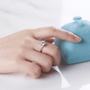 Hand wearing Solara Moissanite engagement ring 💍, showcasing 1.0ct brilliance with a blue ring box in the background. ✨