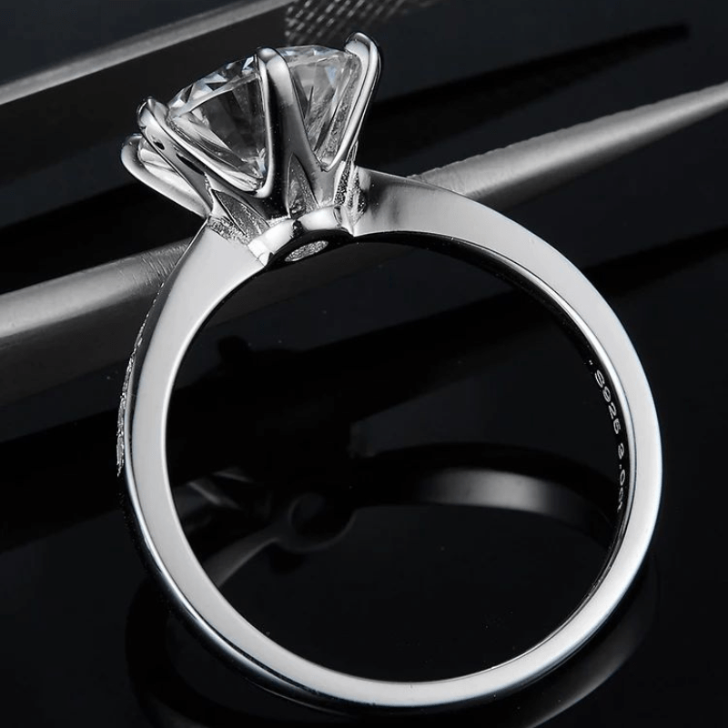 Side view of The Calvienne Round-Cut Moissanite Ring on a black background. Perfect for engagements or weddings! 💍✨