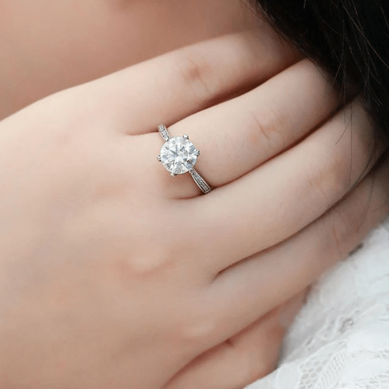 Close-up of a hand wearing a stunning round-cut Moissanite engagement ring with a sleek band. 💍✨ #Moissanite #Wedding