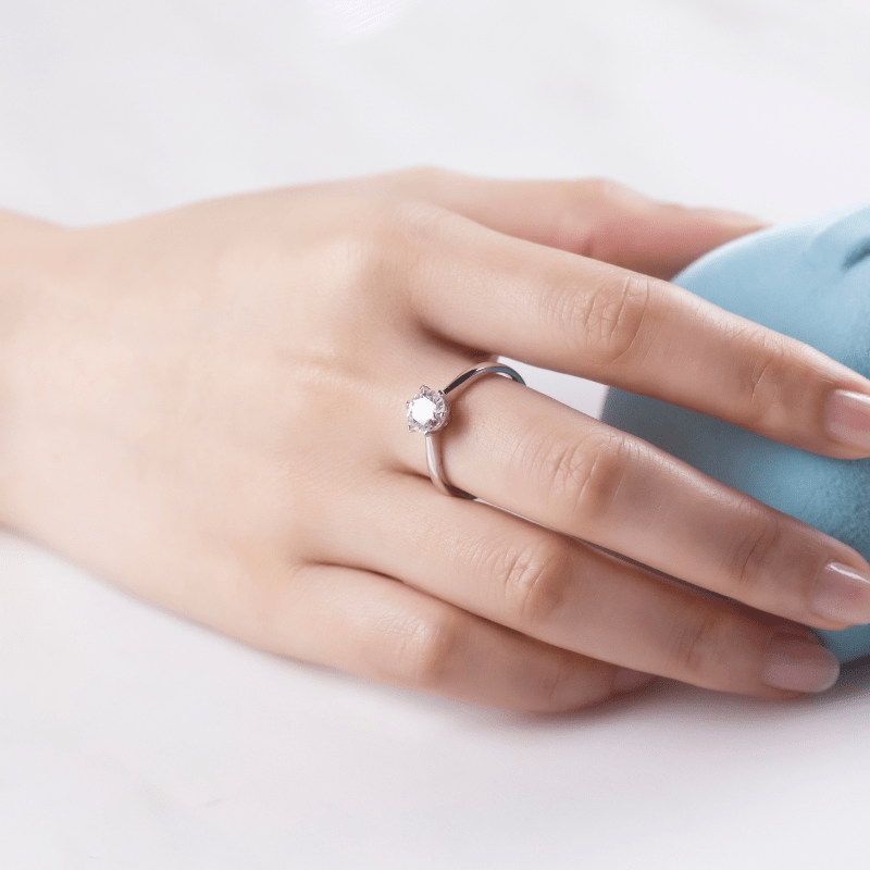 A hand wearing The Camille moissanite engagement ring 💍, showcasing its 1CT brilliance and elegance.