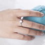 Elegant hand wearing The Elara Moissanite engagement ring 💍✨ with a sparkling center stone and shimmering side stones.