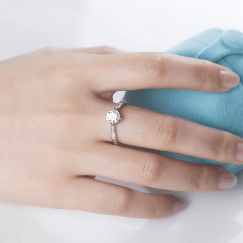 Elegant hand wearing The Elara Moissanite engagement ring 💍✨ with a sparkling center stone and shimmering side stones.