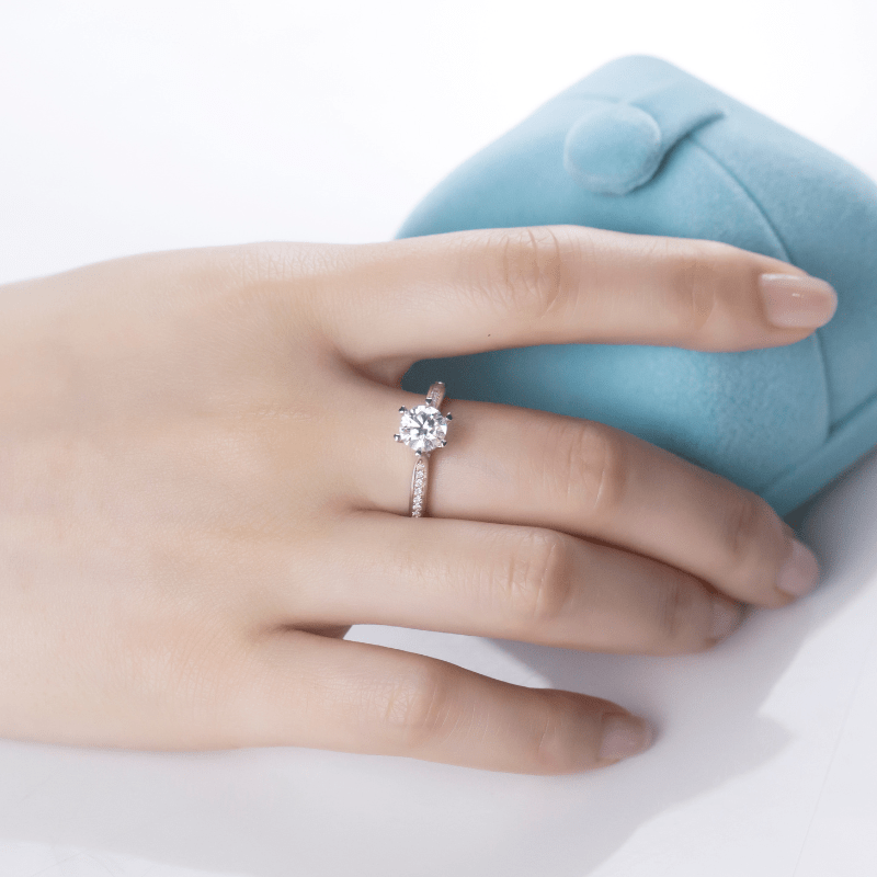 Elegant hand wearing The Elvanna Moissanite Pavé Ring 💍✨ next to a blue jewelry box, perfect for engagement or wedding.