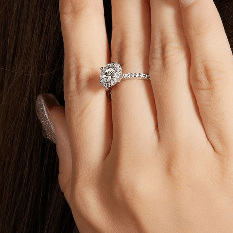 💍 Hand wearing The Evelora Moissanite Halo Ring with a sparkling center stone and pavé band. Elegant engagement or wedding ring. ✨