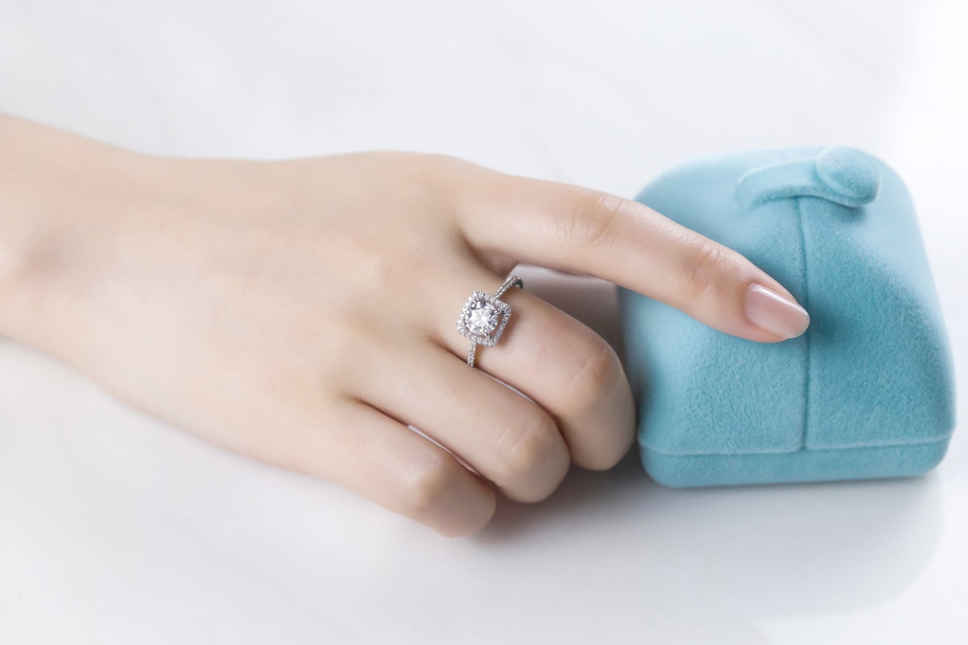 Elegant hand showcasing the Rosalyn Moissanite Halo Ring 💍 next to a soft blue ring box, perfect for engagements and weddings! 💖