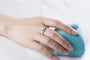 Hand wearing the Rosalyn Moissanite Halo Ring next to a blue ring box 💍✨ Perfect for engagement or wedding! Amazing value!